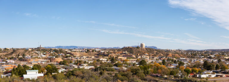Panoramic view of a small desert town across rolling hills under a blue sky