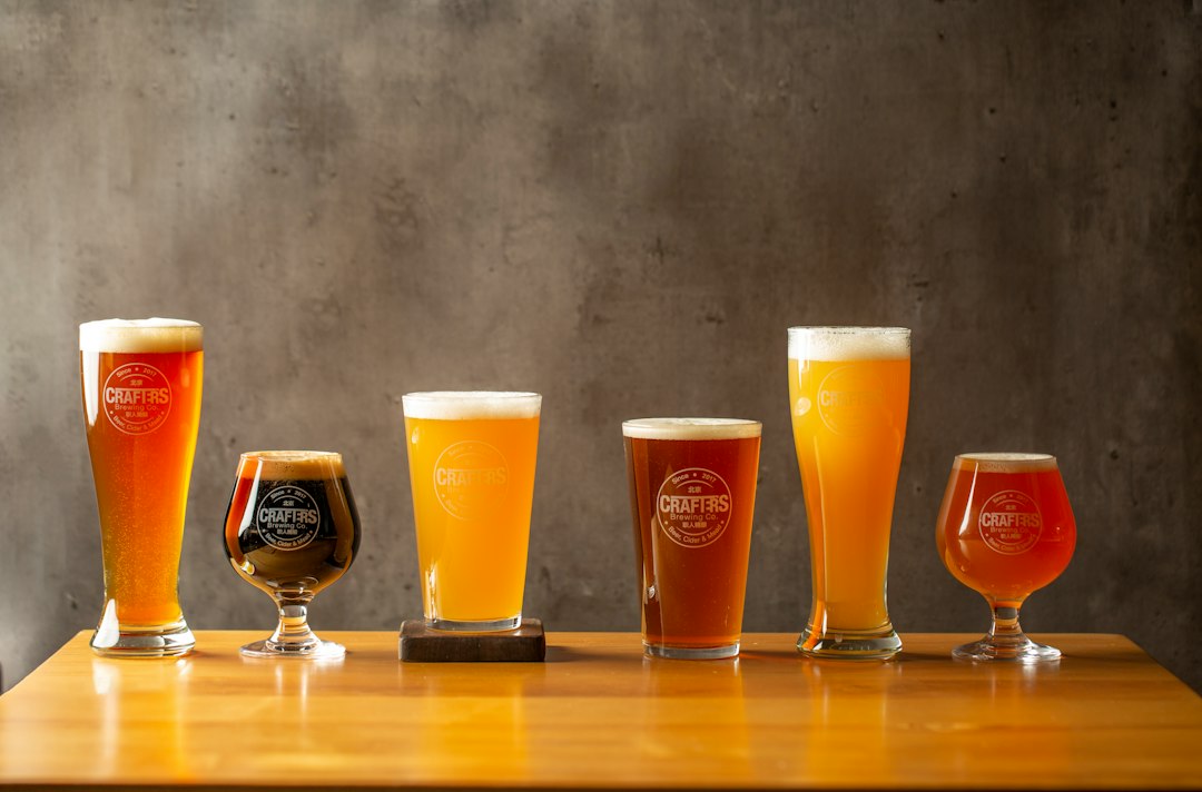 A flight of six beers lined up on a taproom bar, ranging from pale and clear to cloudy and golden.