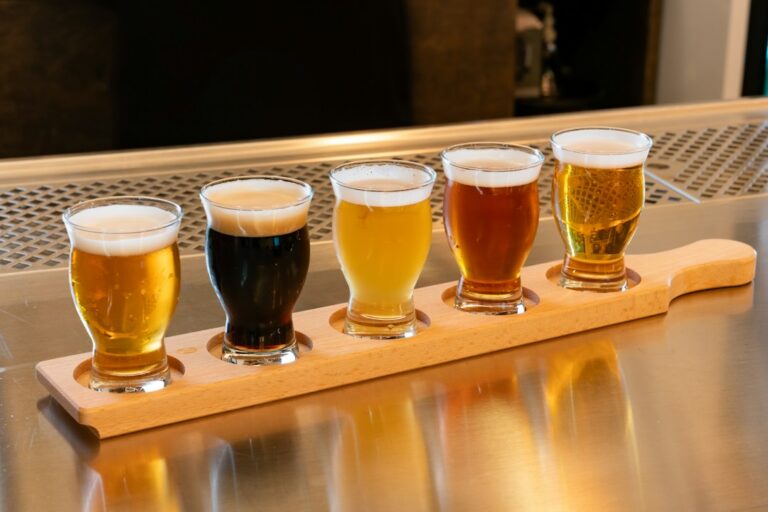 A flight of five beers, from pale gold to dark brown, on a wooden paddle at a bar